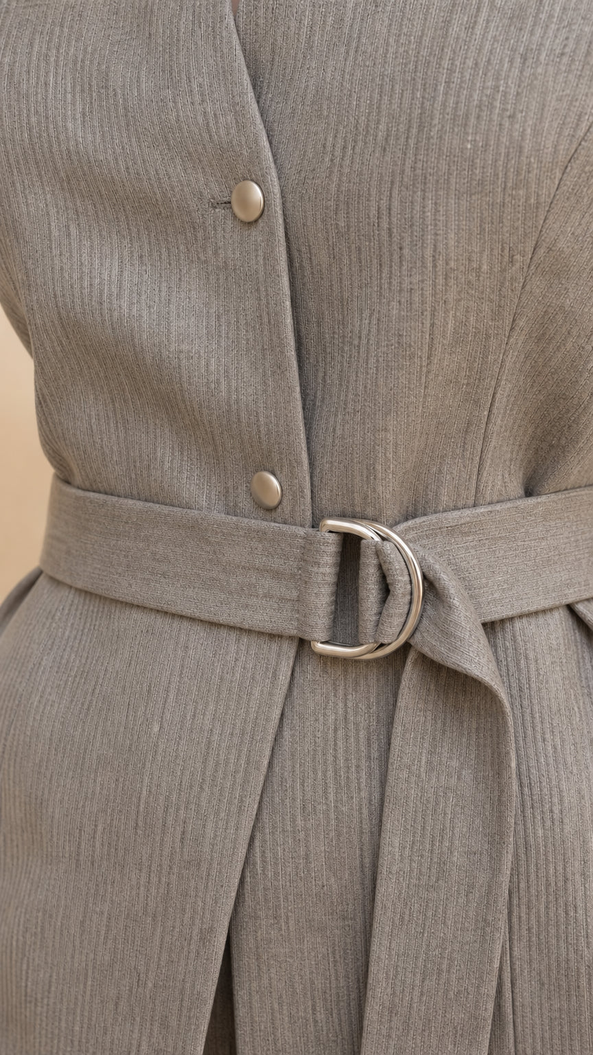Close-up detail of textured woven fabric, buttons, and belt buckle