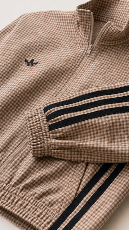Close-up of taupe gingham fabric, front zipper, chest emblem detail, and contrast stripe
