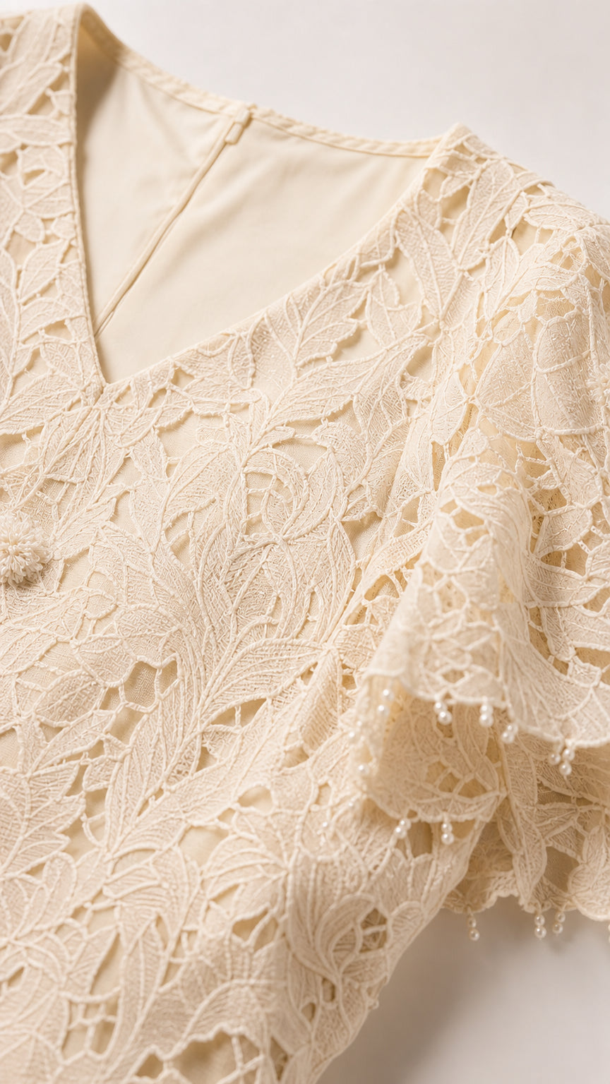 Close-up of V-neckline and flutter sleeve with delicate beaded trim