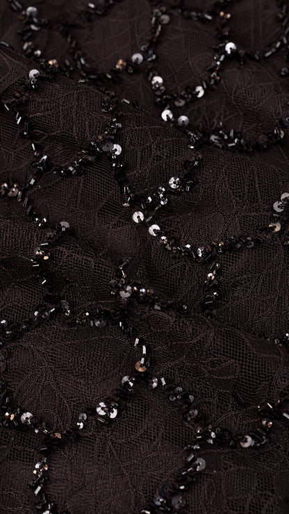 Close-up detail of black sequin embroidery on sheer mesh fabric