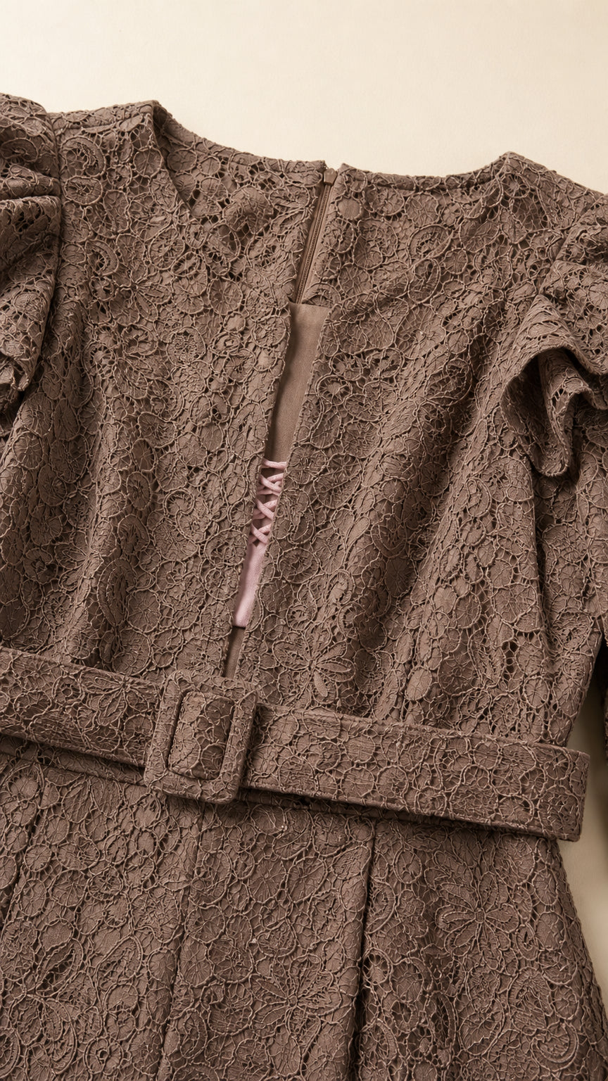 Close-up detail of mocha brown floral lace texture, neckline notch, and buckled belt