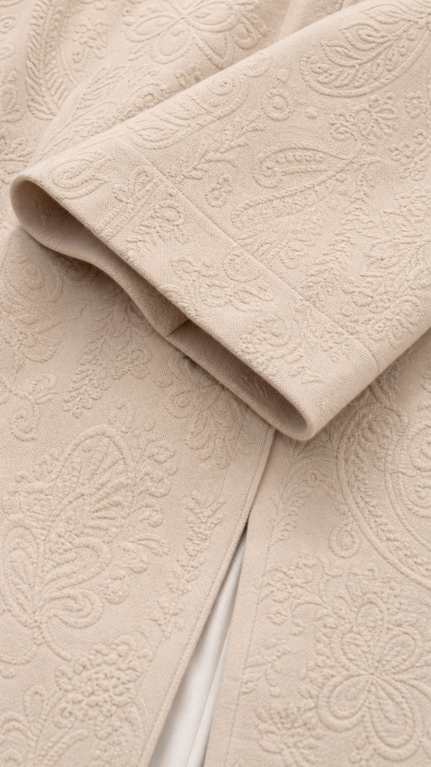 Close-up macro shot of beige embossed paisley textured jacquard fabric and sleeve hem