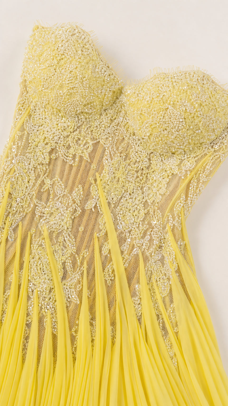 Close-up detail of yellow embroidered lace illusion bodice and pleating