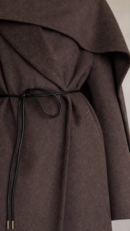 Close-up detail of felted coat fabric and slender black cord waist tie