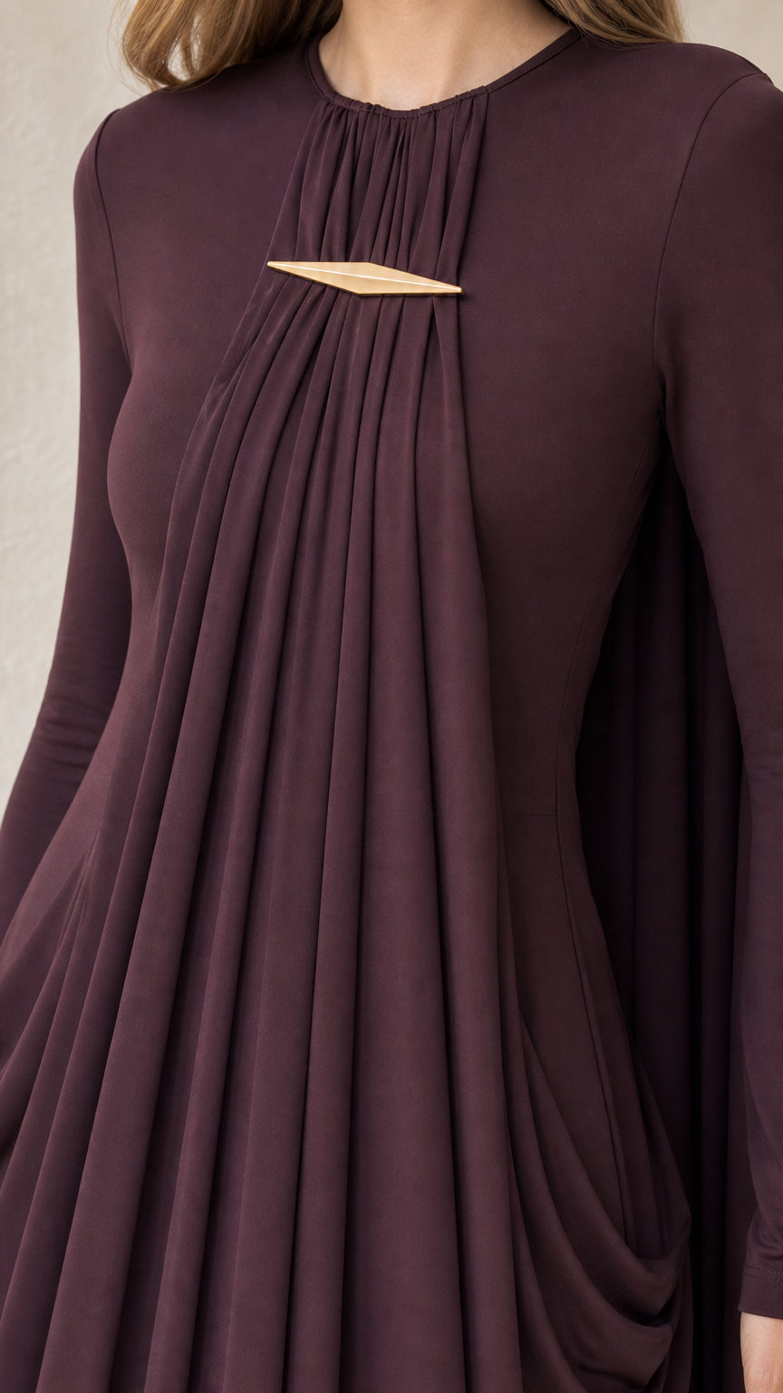 Close-up of gold-tone metallic hardware and gathered front pleating on plum dress