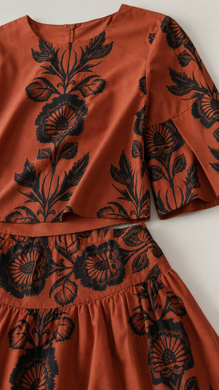 Close-up detail of rust floral patterned fabric, neckline, and waistband