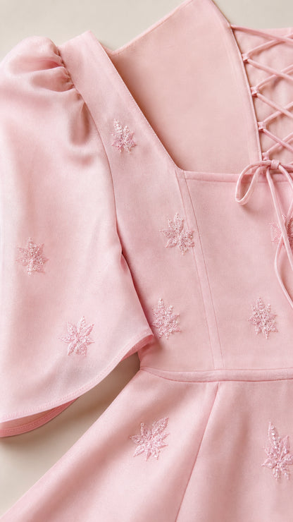 Close-up detail of blush pink neckline, delicate embroidery, and lace-up back