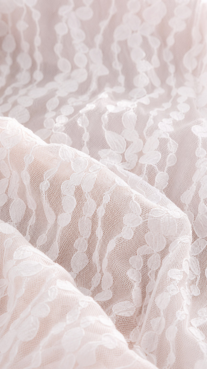 Close-up detail of the delicate patterned lace fabric overlay
