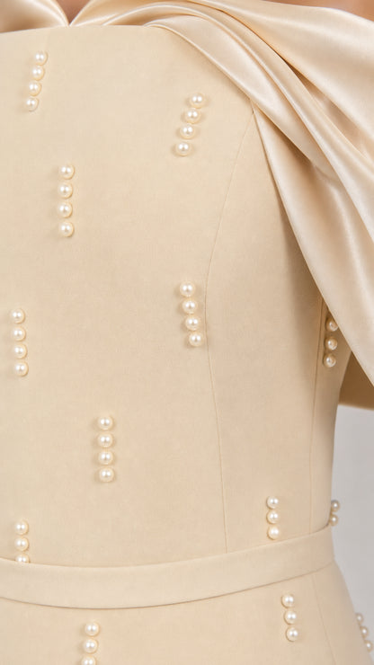 Close-up detail of champagne dress showing delicate pearl beading and satin draped trim