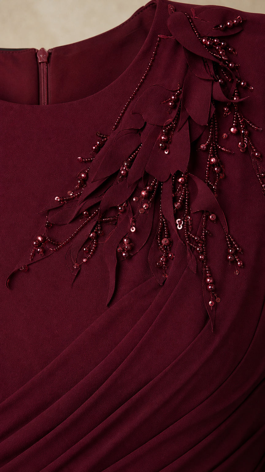 Close-up of beaded floral shoulder detail and pleated bodice on burgundy gown
