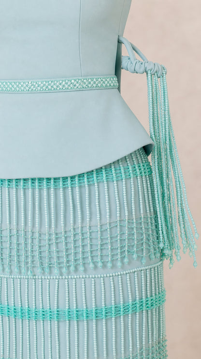 Close-up detail of beaded trim waist, peplum bodice, and fringed arm cuff