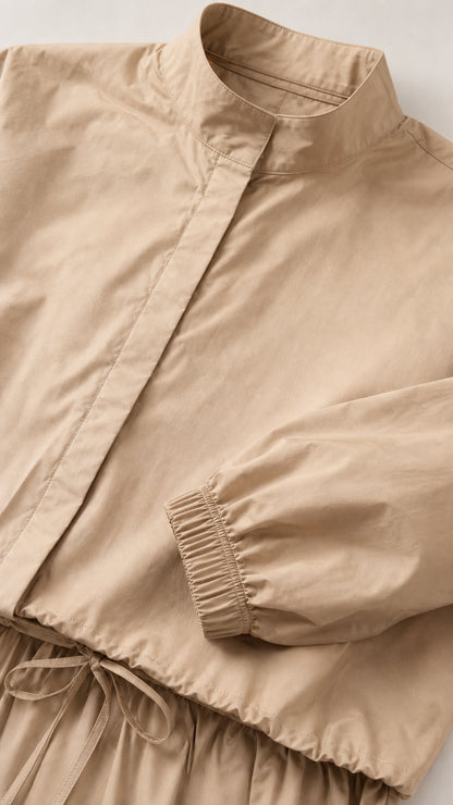 Close-up detail of stand collar, hidden placket, and drawstring waist on beige dress