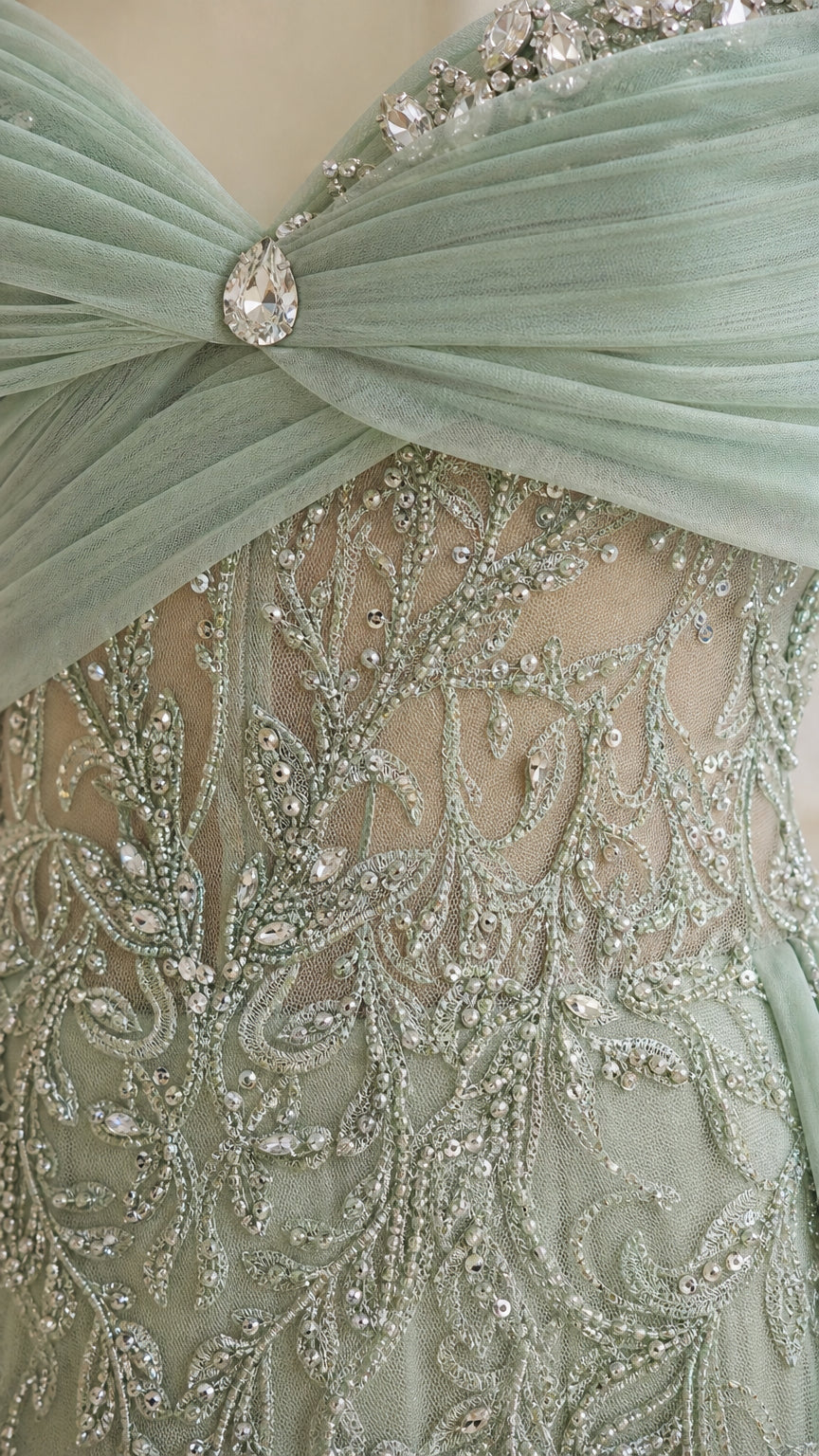 Close-up detail of beaded vine embroidery, crystal brooch, and pleated tulle neckline