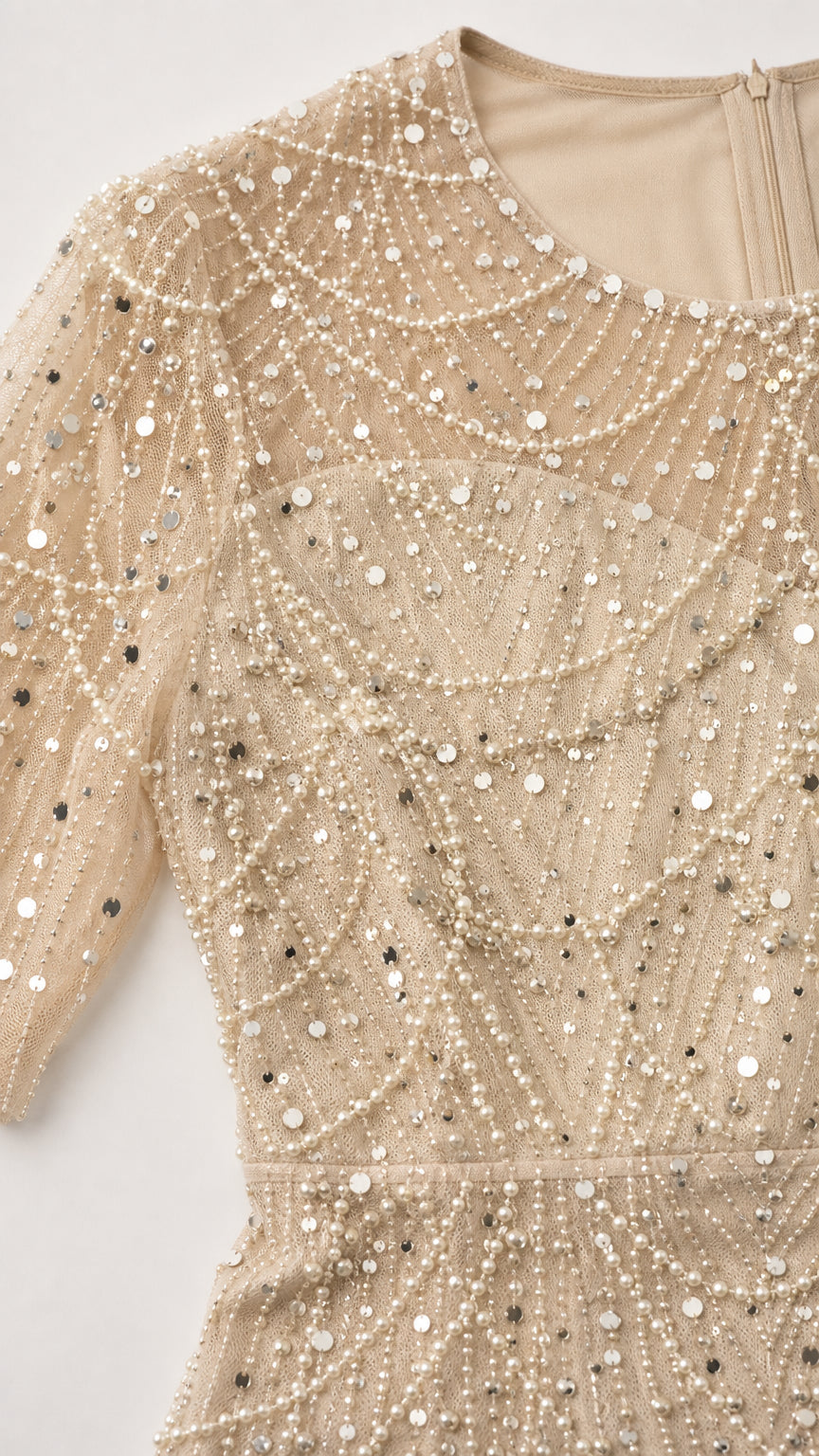 Close-up detail of sheer mesh neckline, pearls, and sequins on formal dress