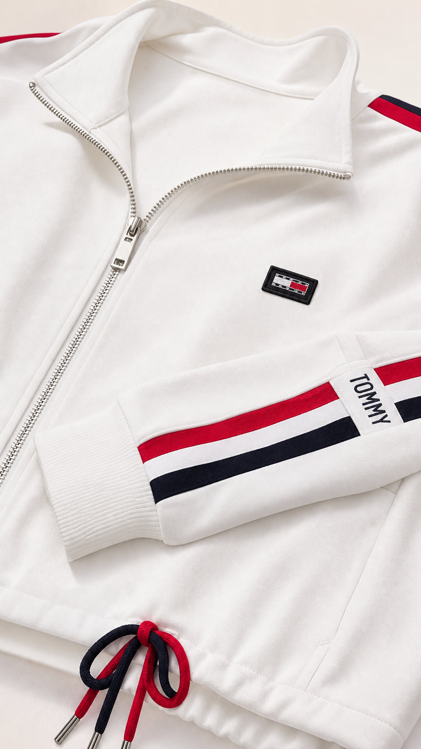 Close-up detail of white jacket collar, zip closure, badge, and striped sleeve cuff