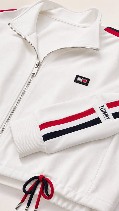 Close-up detail of white jacket collar, zip closure, badge, and striped sleeve cuff