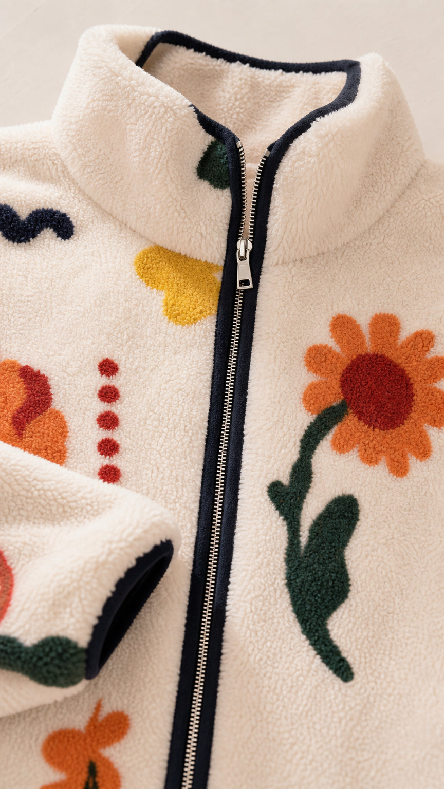 Close-up of the plush cream fleece texture, zipper, collar, and colorful floral print