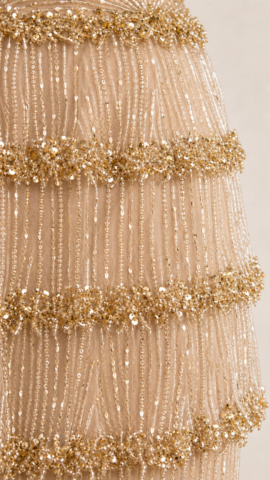 Close-up detail of tiered sequin and bead fringe embellishments on champagne gown