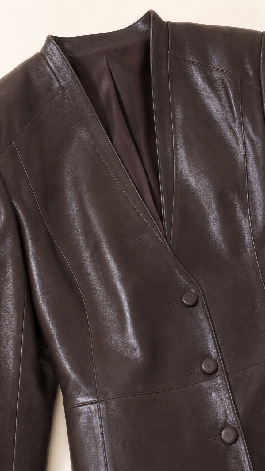 Close-up detail of collarless V-neckline and button closure on Chocolate Brown faux leather blazer