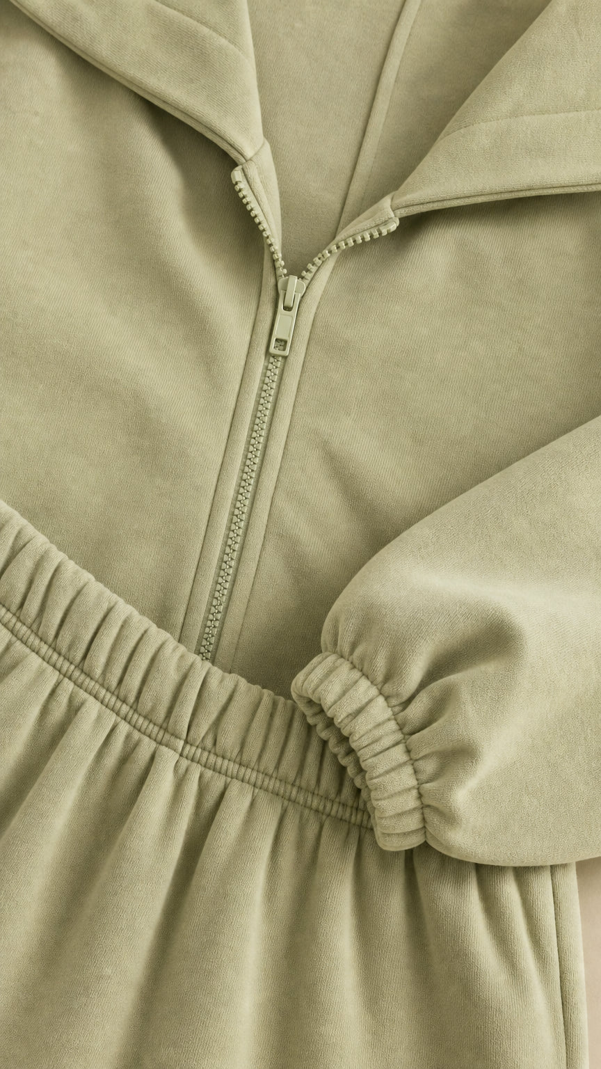 Close-up detail of zipper, elastic waistband, and cuffs on sage green tracksuit