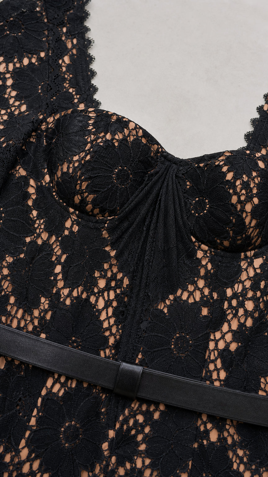 Close-up detail of sweetheart neckline, lace fabric, and waist belt on black dress