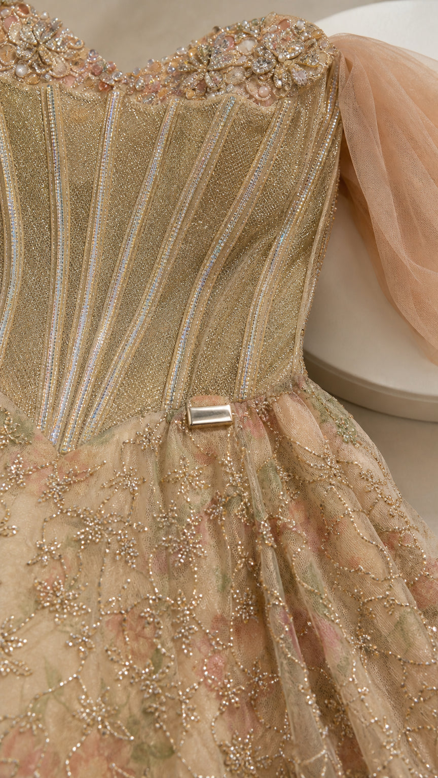 Close-up detail of champagne gold boned corset with beadwork and tulle sleeve