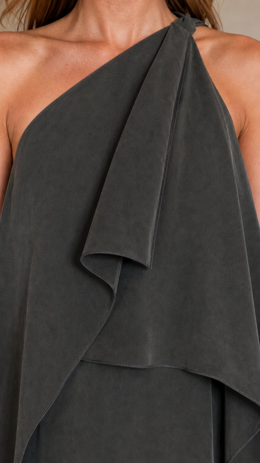 Close-up detail of one-shoulder neckline and cascading overlay on dark grey dress