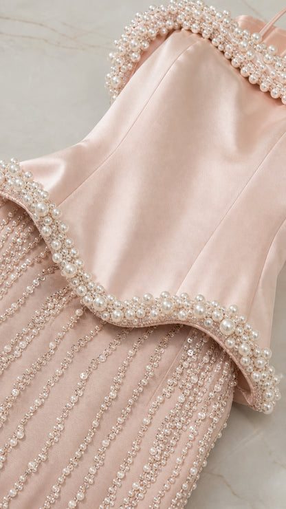 Close-up detail of the satin bodice, pearl trim, and vertical beaded skirt craftsmanship