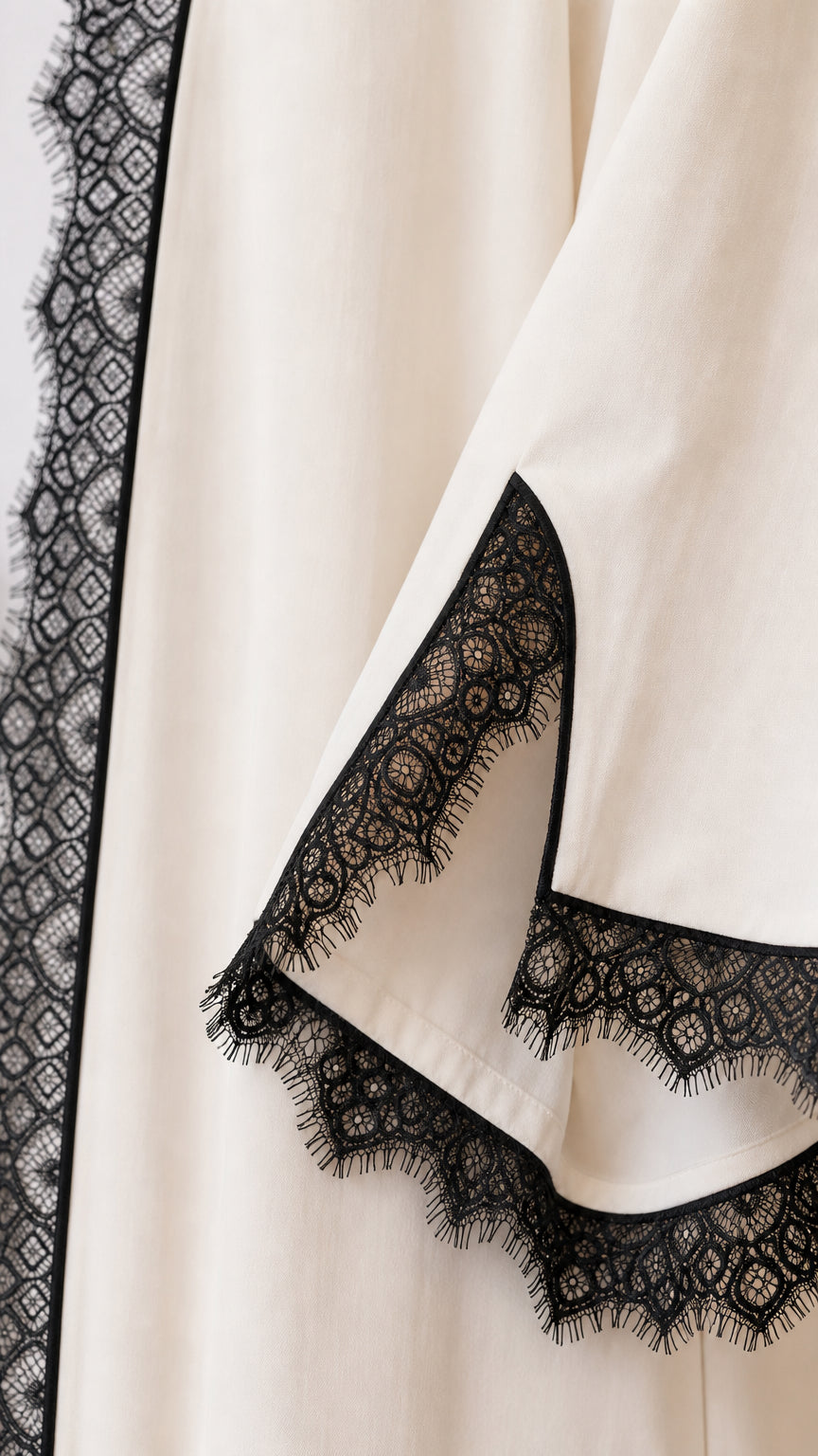 Close-up detail of delicate black eyelash lace trim on sleeve cuff and garment hem
