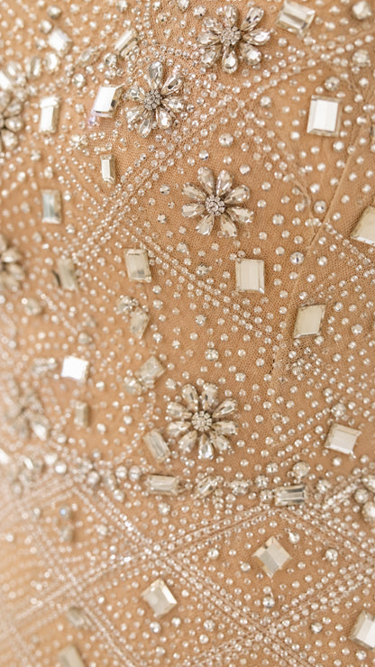 Close-up detail of geometric beadwork and floral crystal clusters on champagne mesh