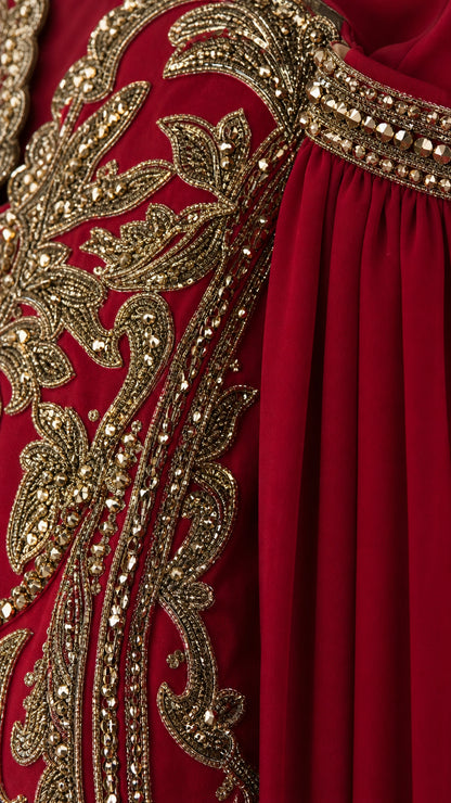 Close-up detail of ornate gold metallic embroidery and beaded accents on burgundy fabric