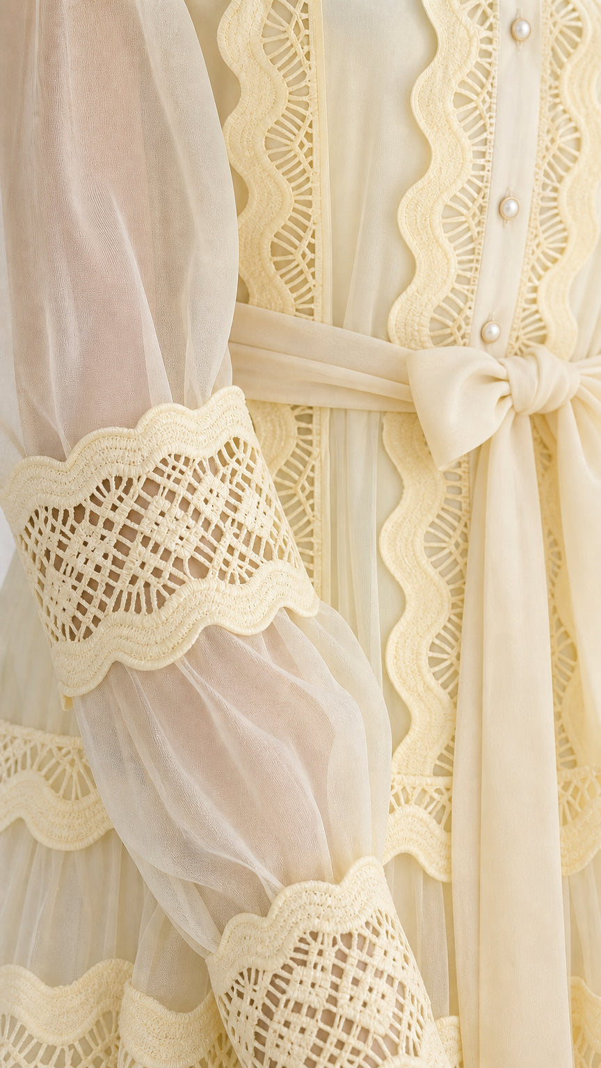 Close-up detail of sheer fabric, intricate openwork lace trims, and tie sash