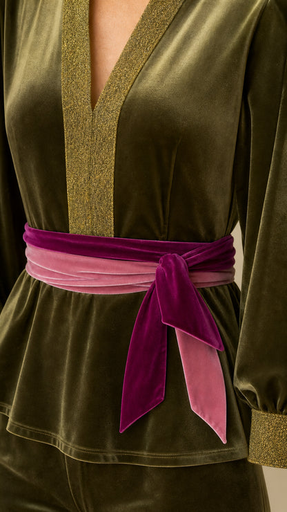 Close-up detail of glittering V-neckline trim and contrast tie belt on olive velvet top