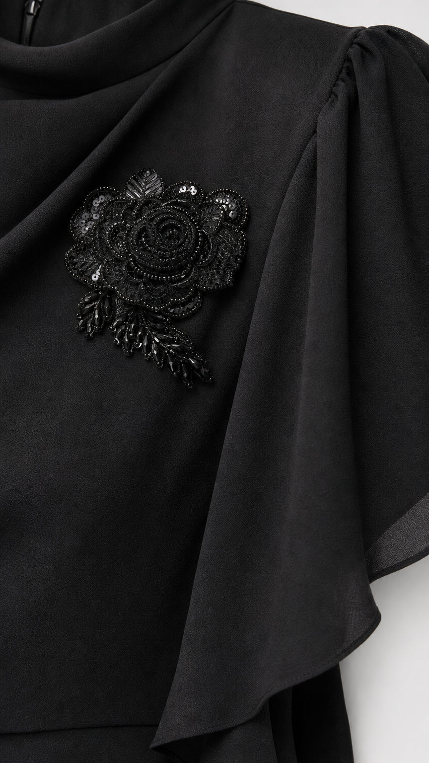 Close-up of black beaded floral applique on draped shoulder of gown