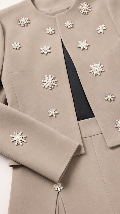 Close-up detail of crystal and pearl starburst embellishments on taupe fabric