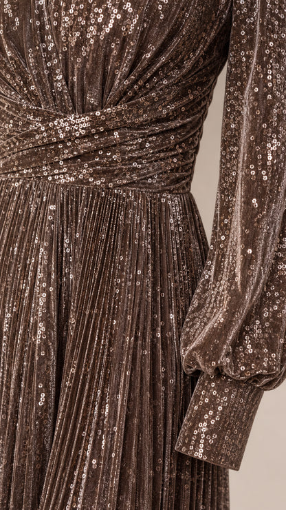 Close-up detail of sequin fabric, crossover waistband, and pleated skirt