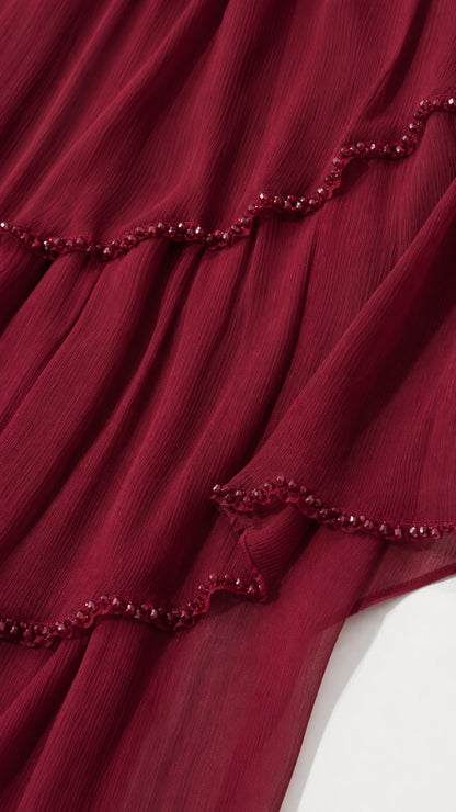 Close-up detail of burgundy pleated chiffon fabric and delicate beaded edge trim