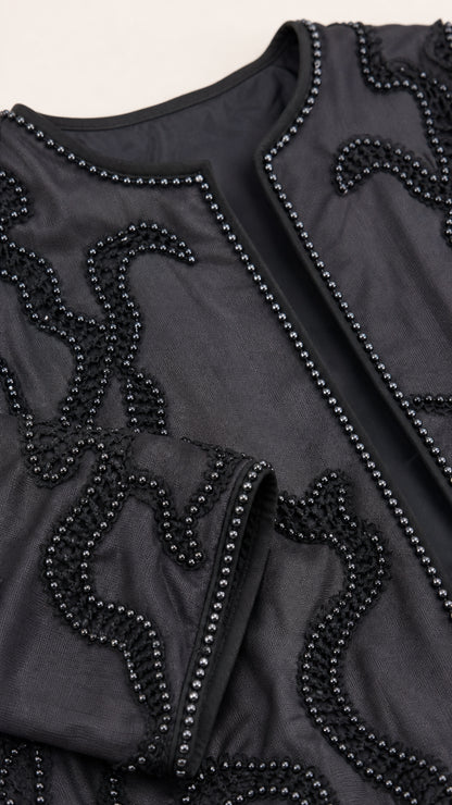 Close-up detail of black beaded swirl embroidery and edging