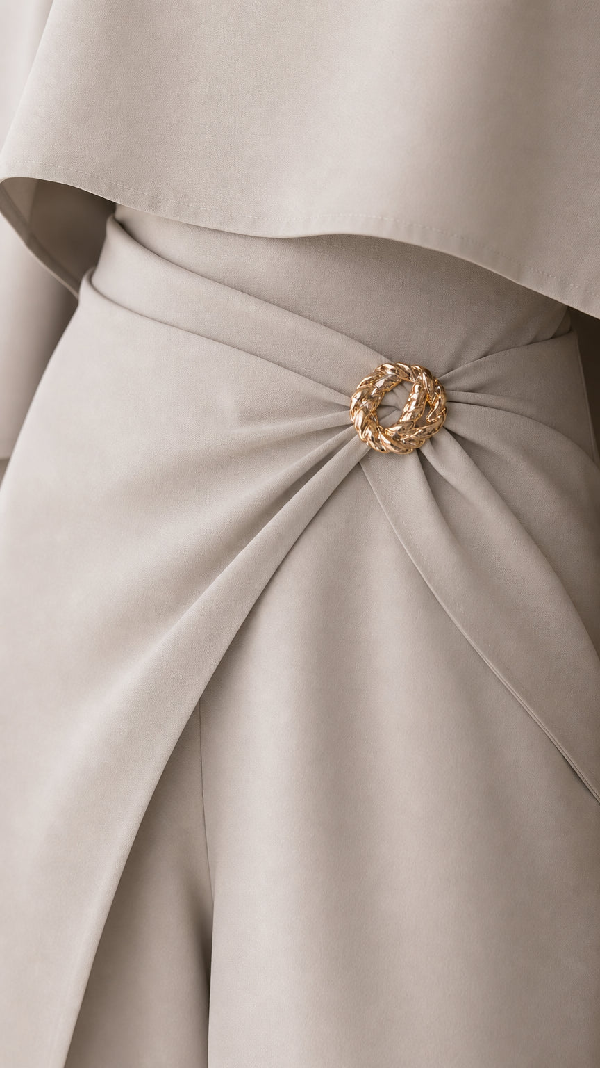 Close-up detail of textured gold ring brooch on draped waistline