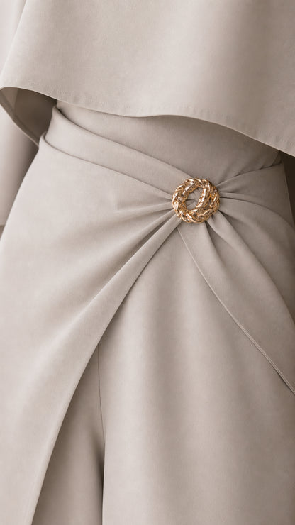 Close-up detail of textured gold ring brooch on draped waistline