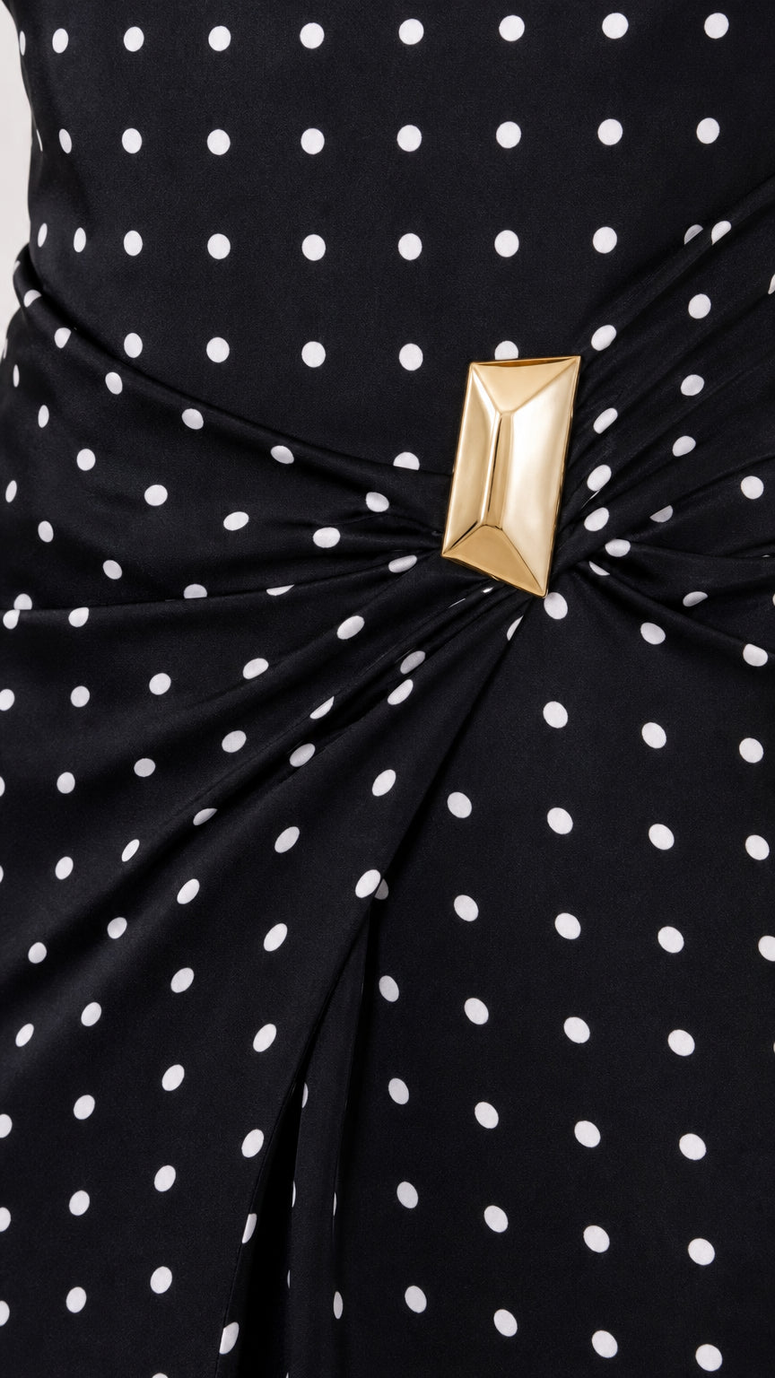 Close-up detail of ruched waist and gold-tone geometric buckle on black polka dot dress