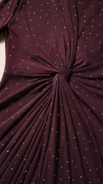 Close-up detail of twist knot waist and sparkling rhinestone embellishments on dark fabric