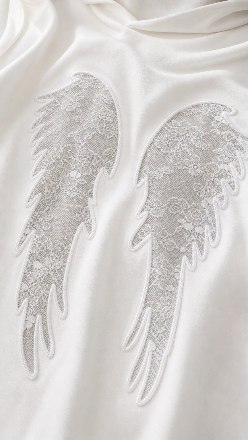 Close-up detail of lace angel wings applique on soft knit fabric