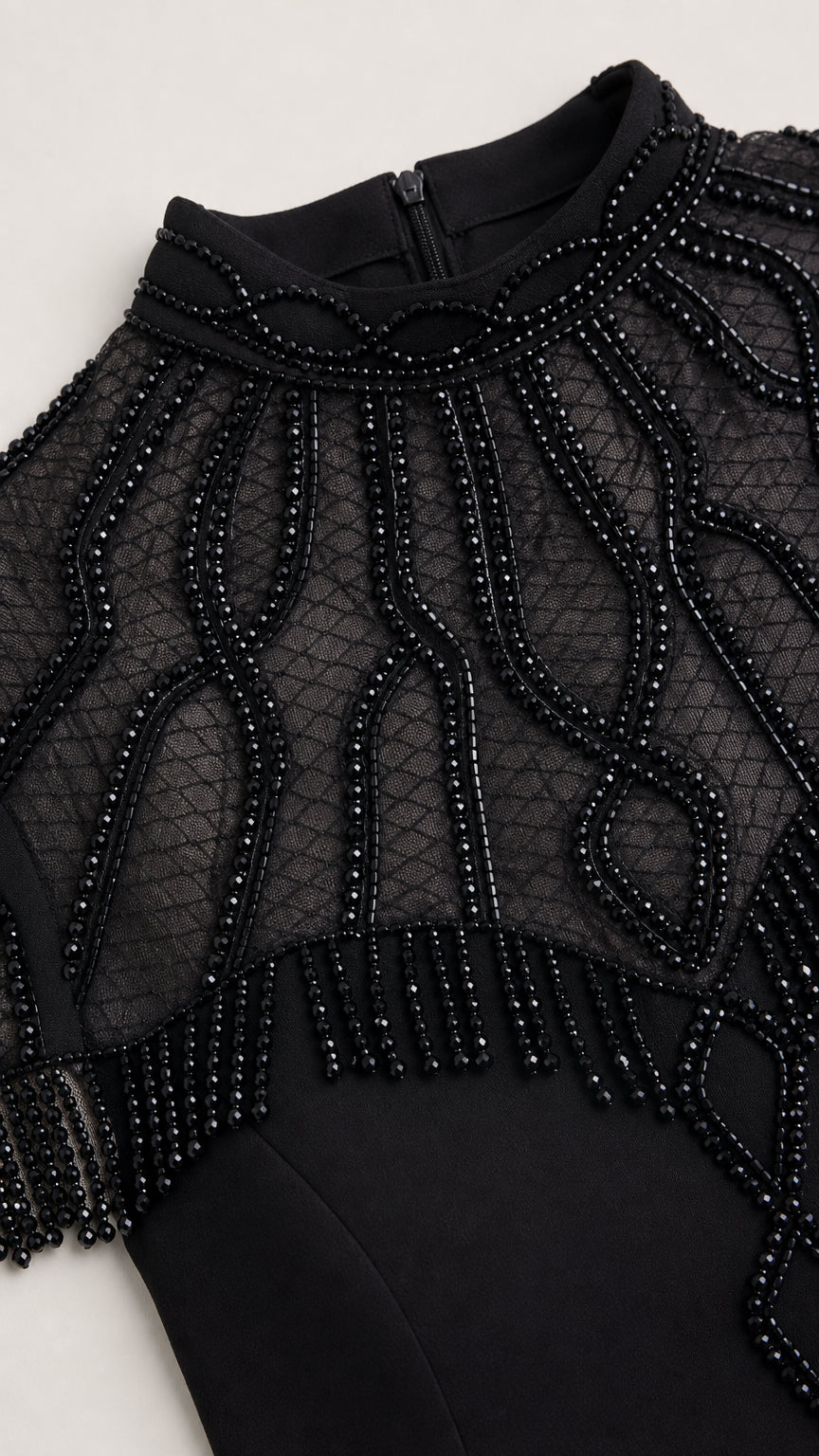 Close up view of intricate beaded illusion mesh neckline and fringe detail