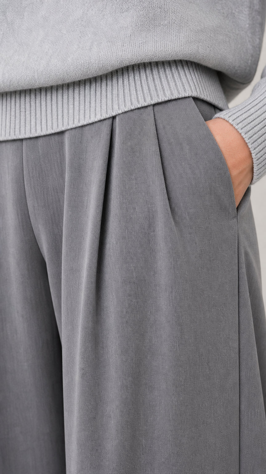 Close-up detail of sweater ribbed hem and tailored trouser waistband