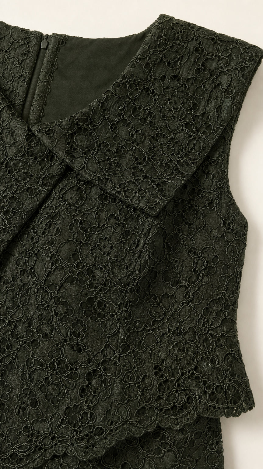 Close-up detail of dark green intricate floral lace fabric and lapel collar
