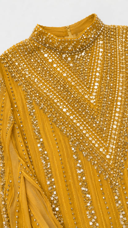 Close-up detail of ornate beadwork and sequin embellishments on mustard yellow neckline