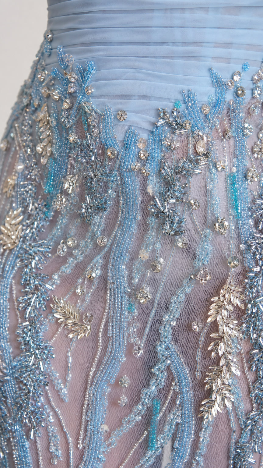 Close-up detail of light blue gown showing ruched bodice and intricate silver and blue beading on sheer fabric
