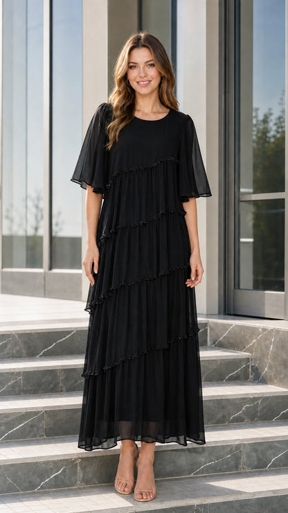 Front view of woman wearing black tiered chiffon maxi dress with flutter sleeves