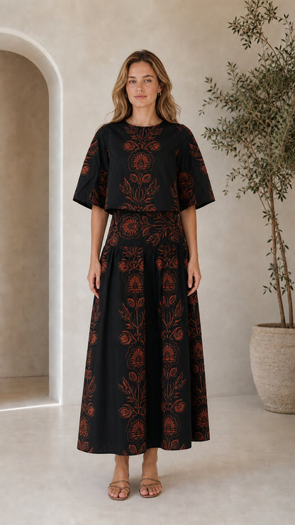 Woman wearing black floral print crop top and tiered maxi skirt two-piece set